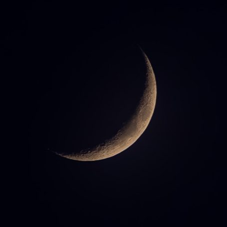 Dünner, zunehmender Mond auf einem dunklen Hintergrund.